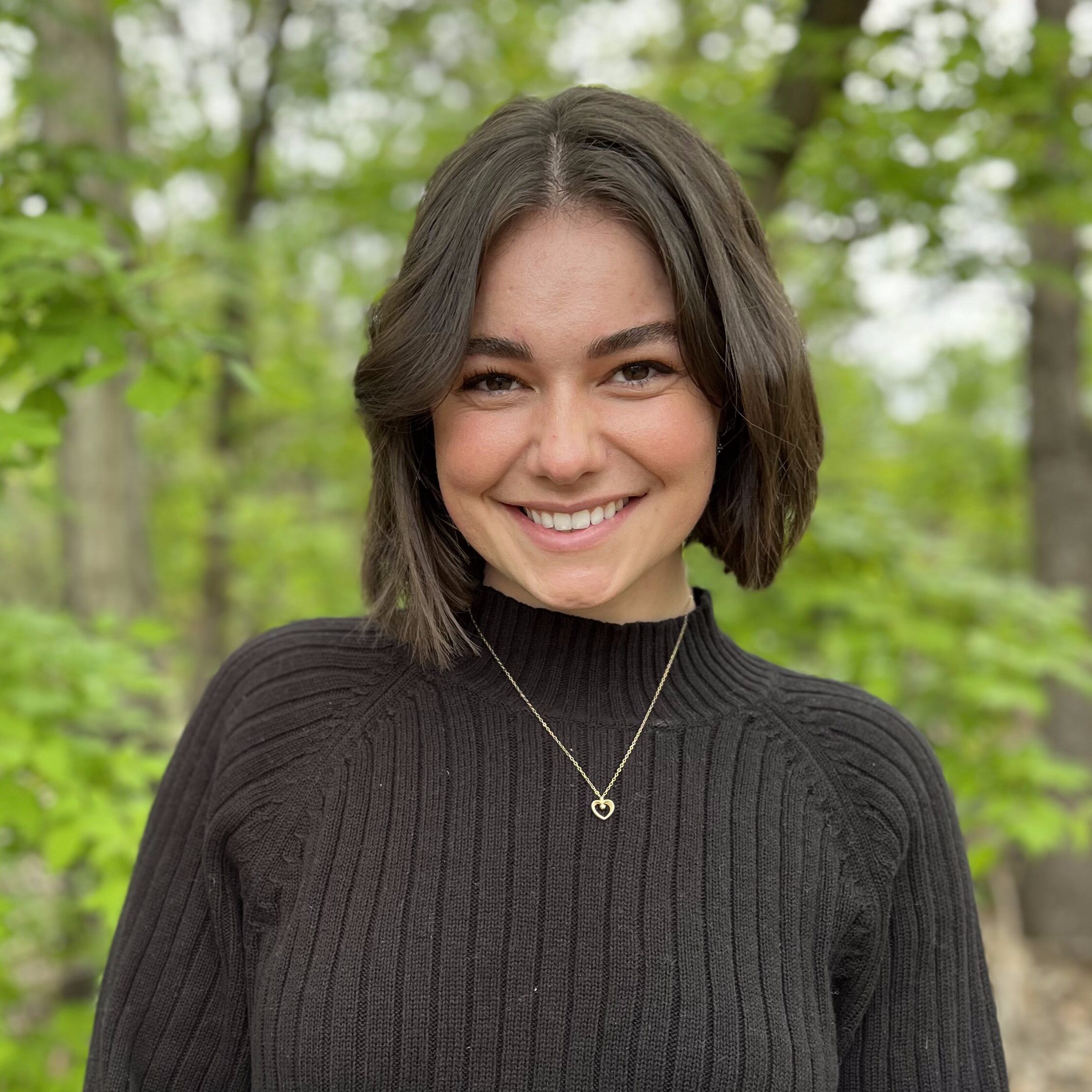 A headshot photo of Amy Manske, Speech-Language Pathologist at Granville Island Speech. She stands in front of a forest.