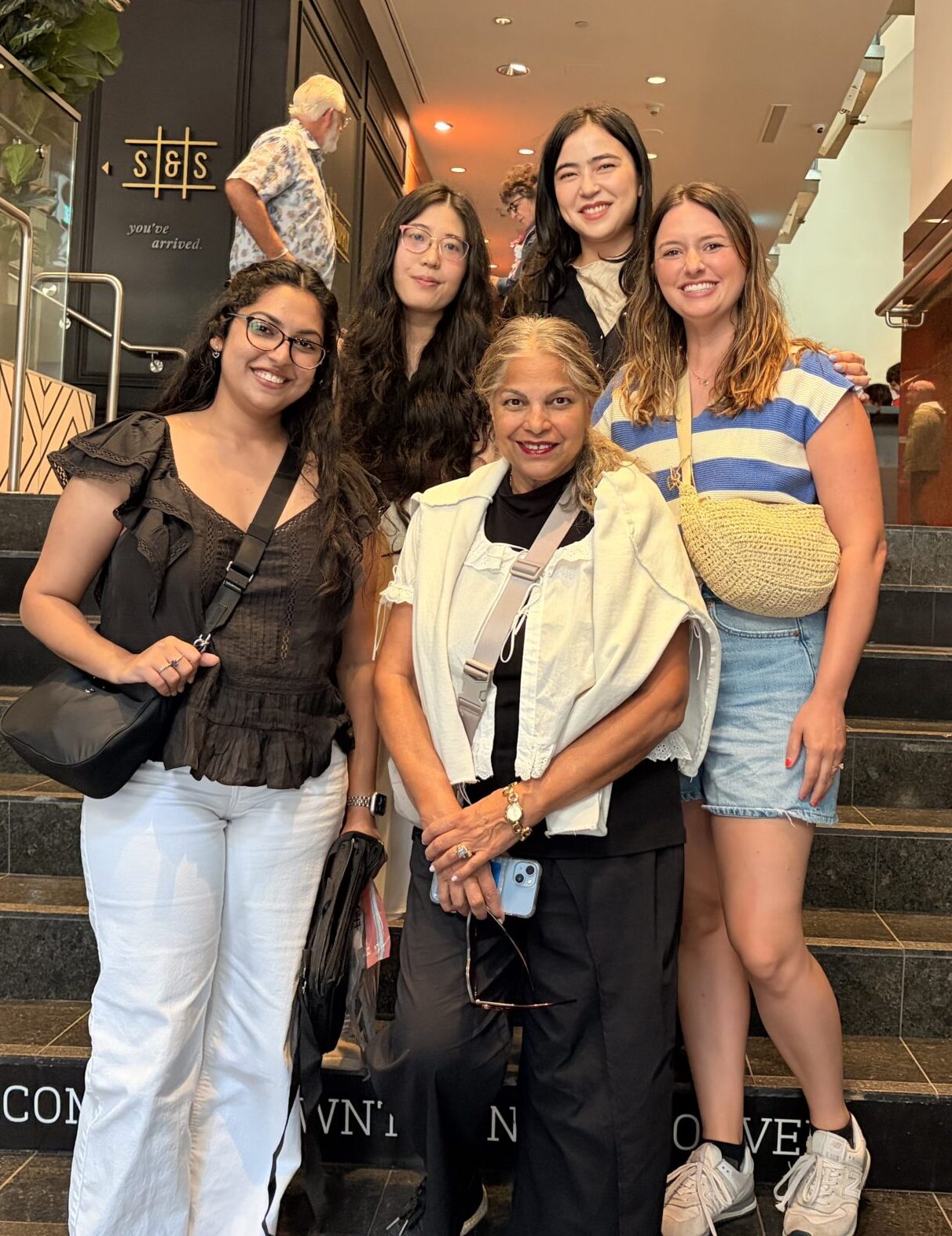 A photo of Vinni with her team standing on the stairs of a building outside a restaurant after a team social. 